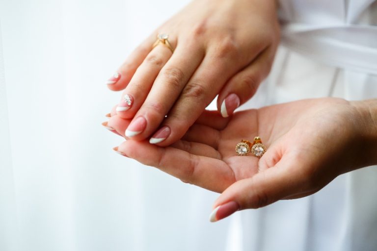 Personne nettoyant délicatement des boucles d’oreilles en or avec un chiffon doux et de l’eau savonneuse