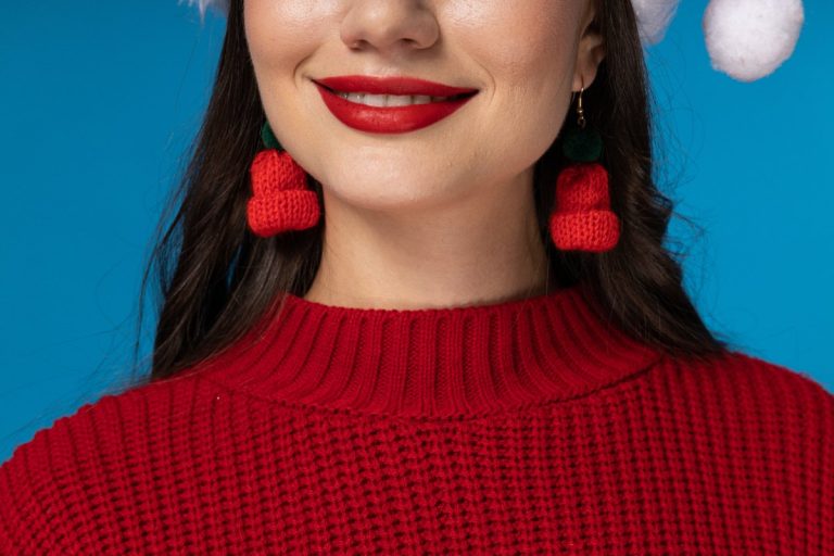 Une paire de boucles d’oreilles dorées repose dans un écrin décoré pour Noël