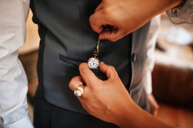 Montre à gousset glissée dans la poche d’un gilet, chaîne attachée au bouton