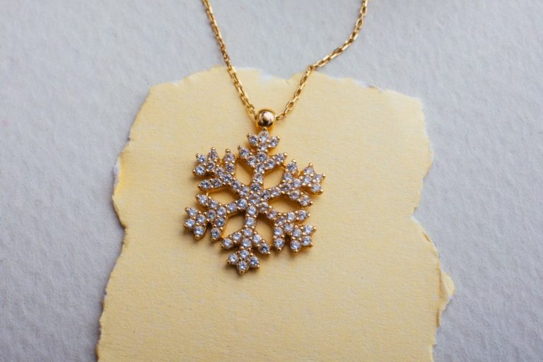 Un pendentif doré repose dans un écrin décoré aux couleurs de Noël
