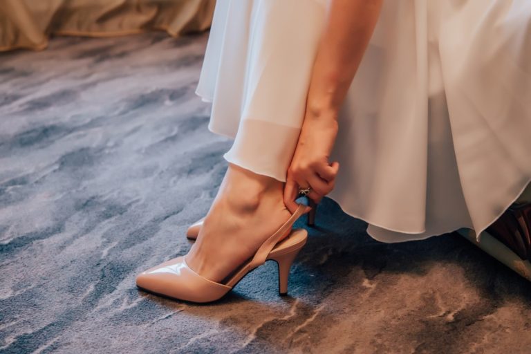 Une femme assise qui met ses chaussures qui vont bien avec sa robe longue