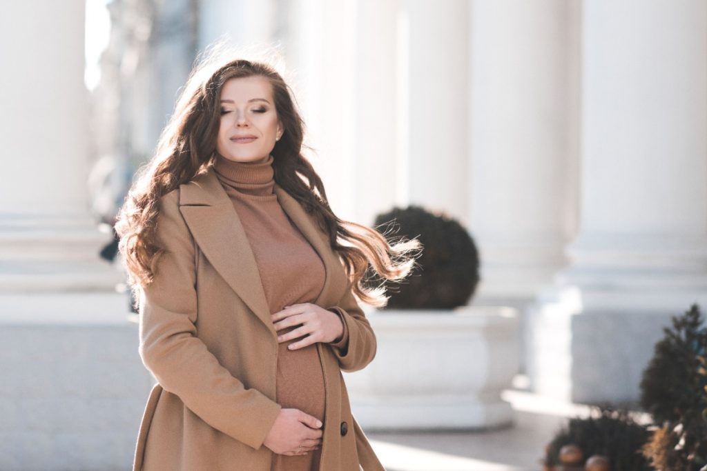 Une femme enceinte portant une robe et un manteau marron