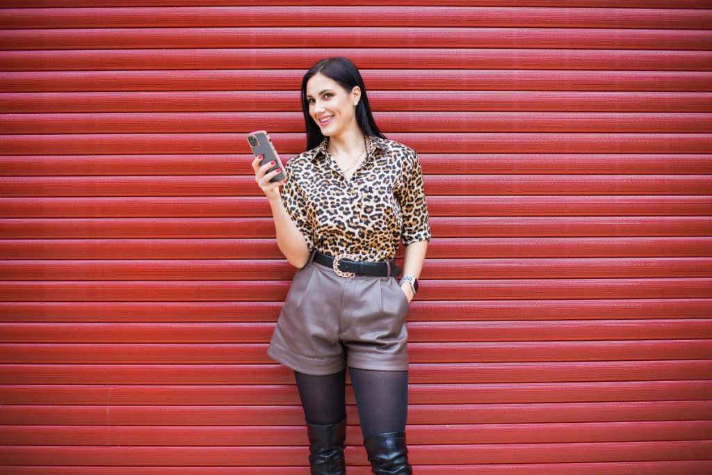 Une femme habillée avec une chemise imprimée python et un short gris