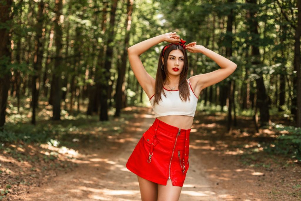 Une femme portant une jupe rouge en cuir et et petit haut blanc
