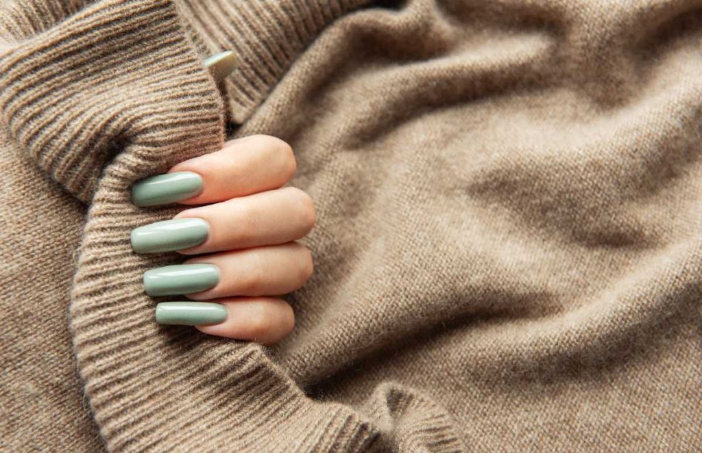 Une jolie main aux ongles longs de couleur vert kaki