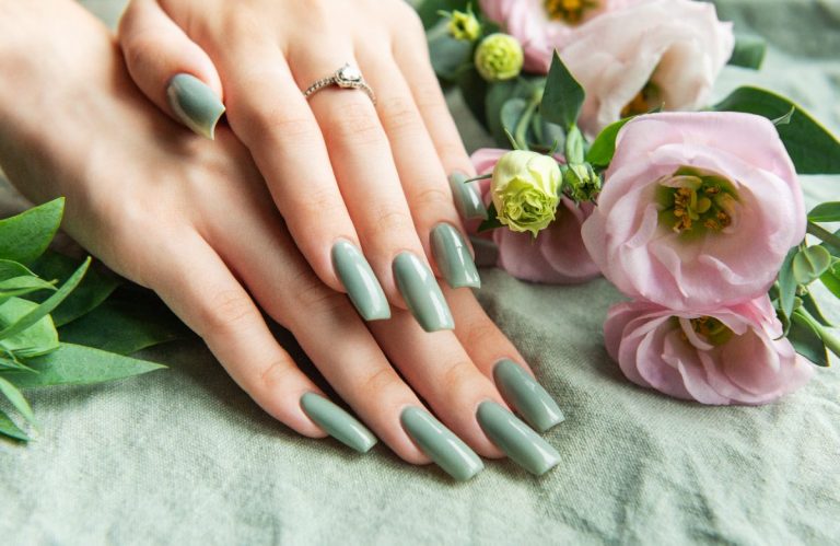 Des mains élégantes avec du vernis à ongle kaki