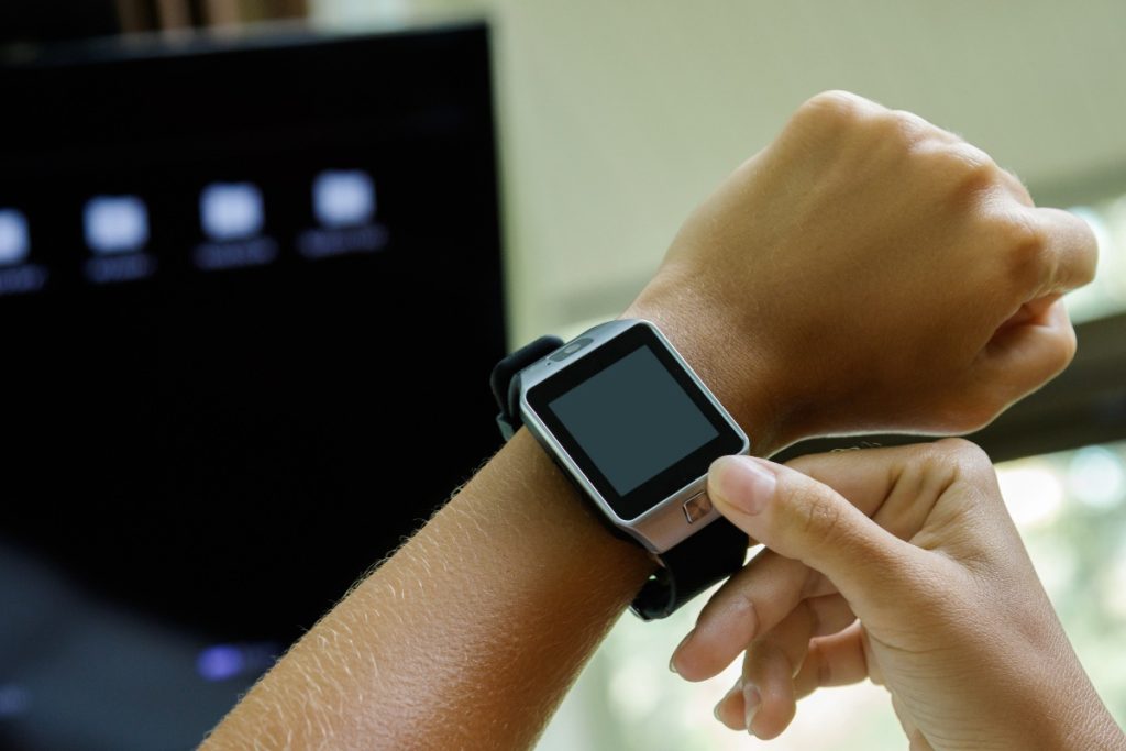 Main appuyant sur le bouton d'une montre connectée