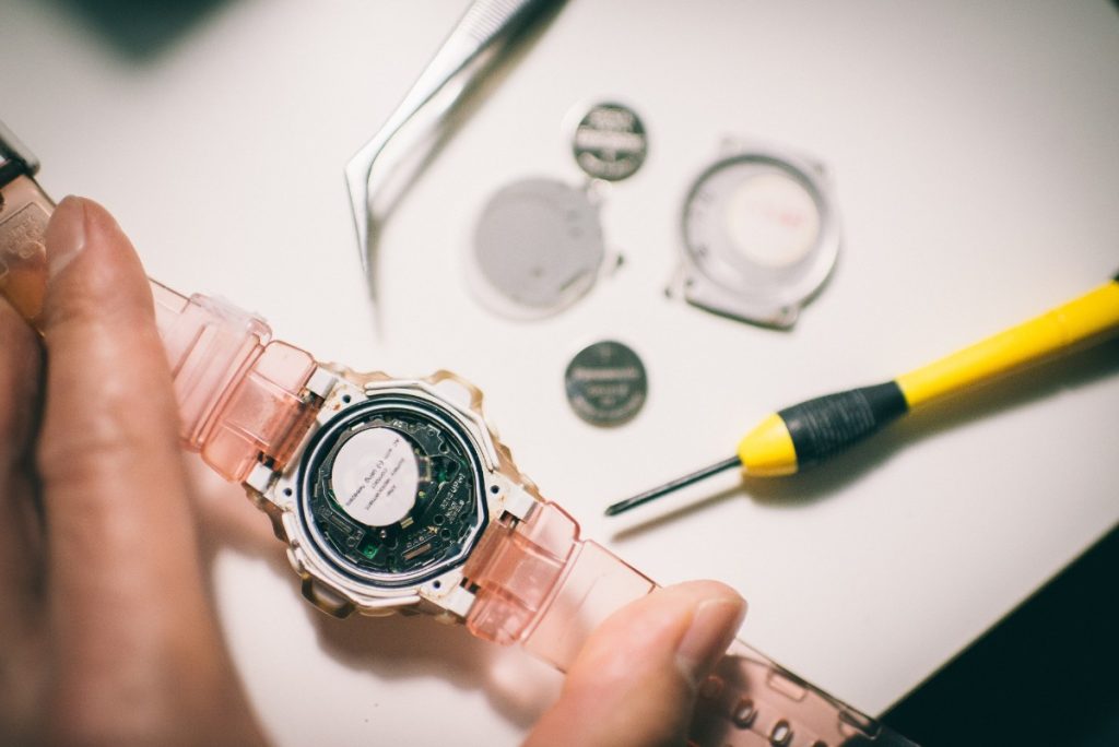 Des mains réparant une montre sur la table