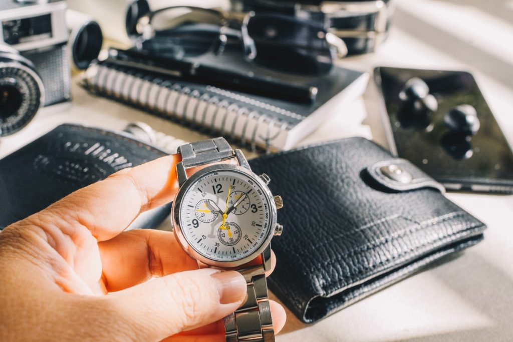 Une personne tenant une montre près des portefeuilles