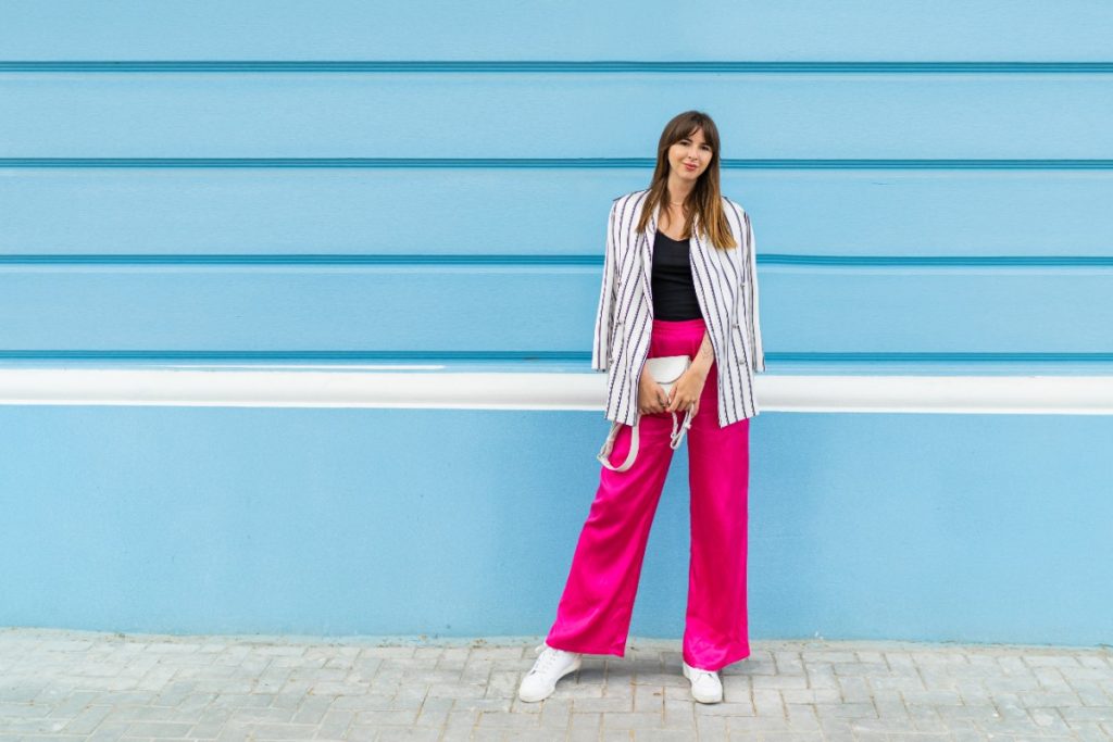 Une femme en pantalon large rose et un basket blanc