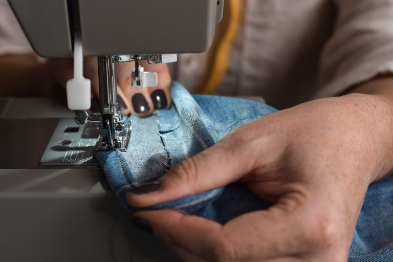 Main cousant un pantalon sur la machine