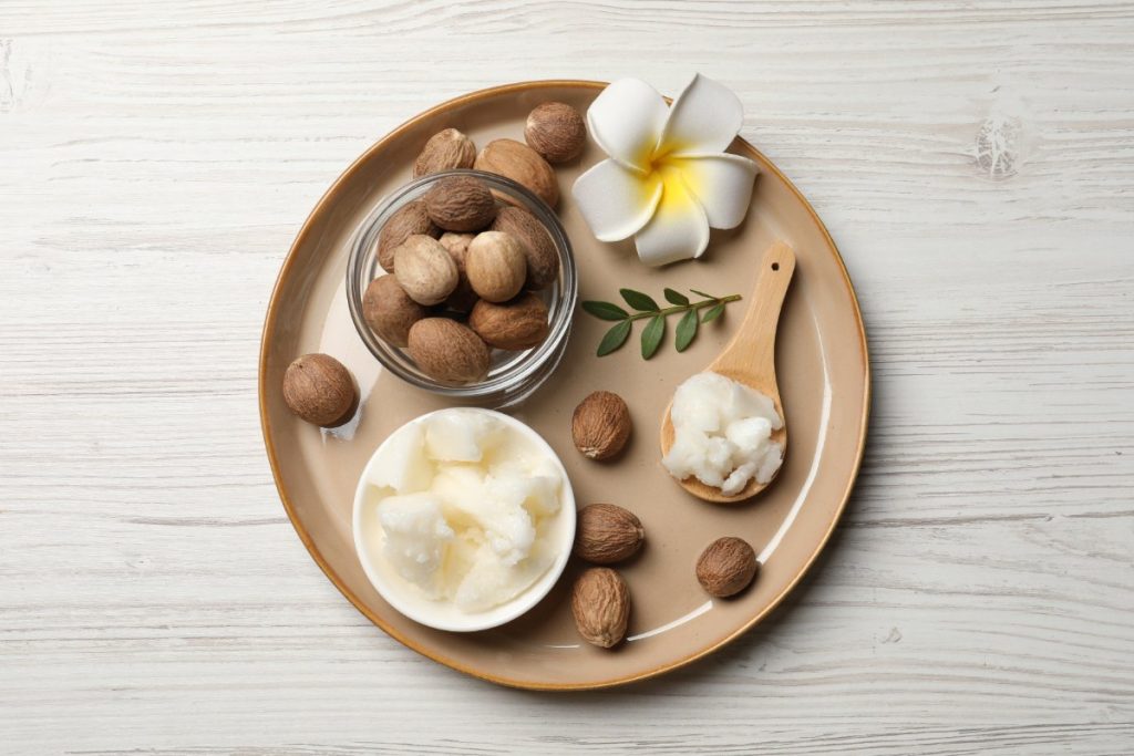 Beurre de karité dans un bol avec des noix et de fleur de pluméria