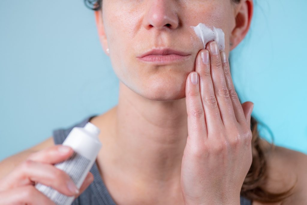 Une femme appliquant une crème sur le visage