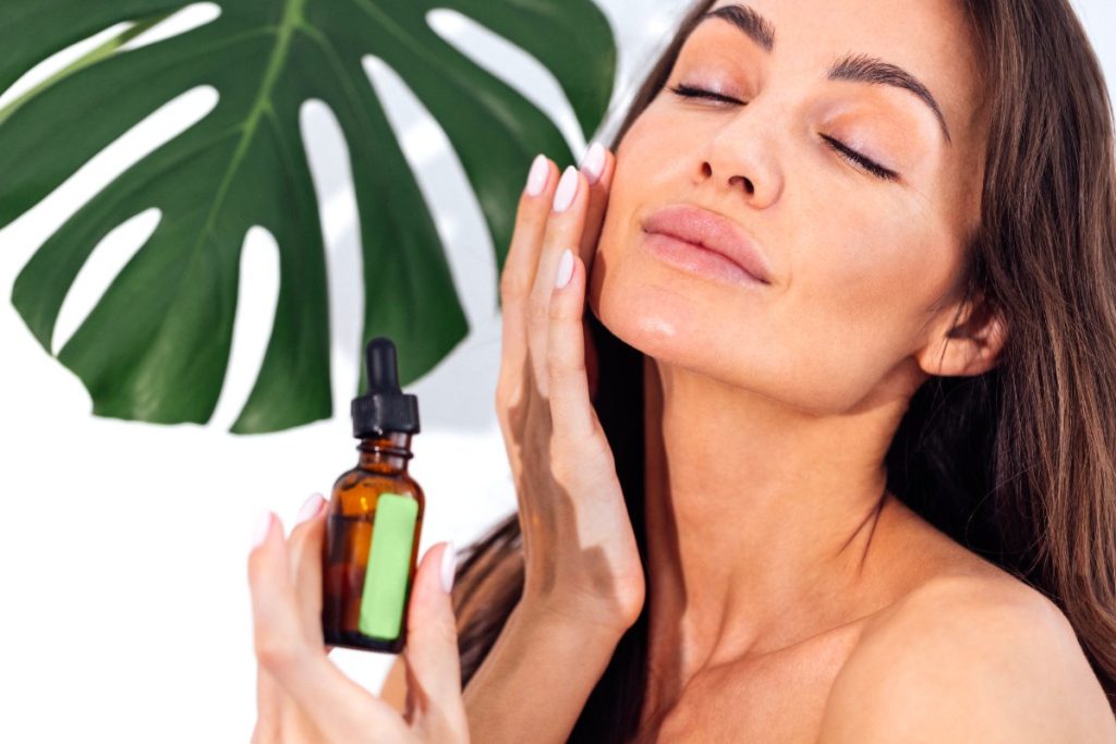 Une femme appliquant de l'huile de chanvre sur le visage