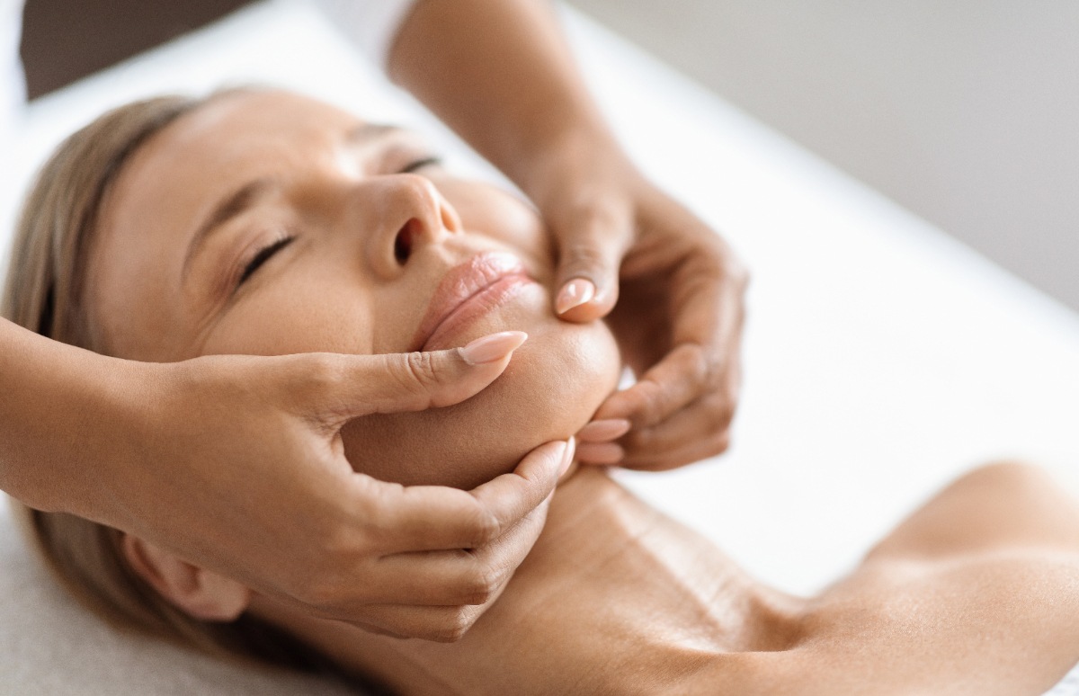 Une femme détendue qui reçoit un massage du visage