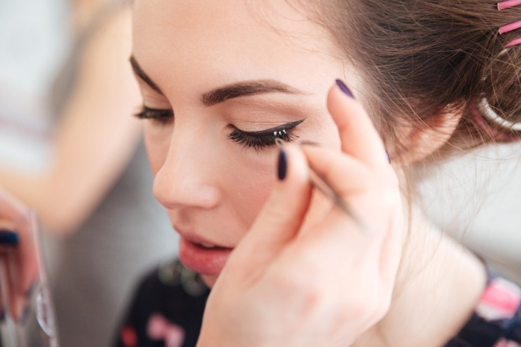 Une femme qui se fait poser des faux cils dans un salon de beauté