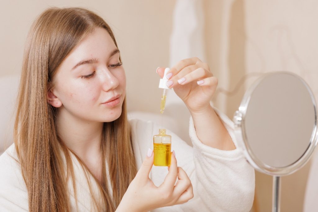 Une femme qui tient un flacon d'huile de visage
