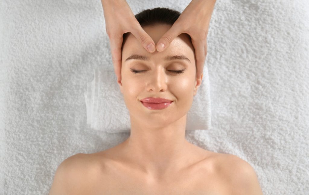 Une femme heureuse recevant un massage relaxant du visage