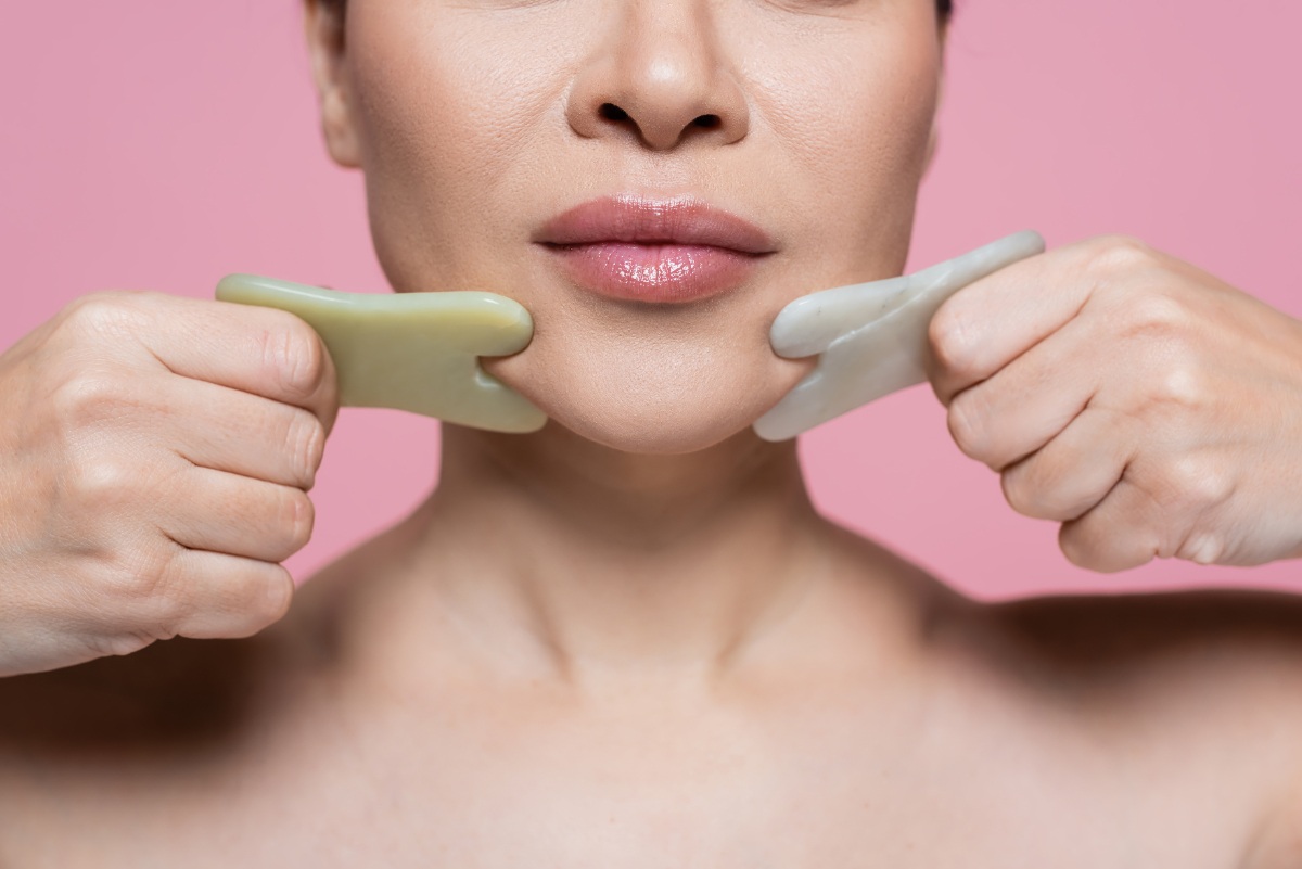 Une femme massant son visage avec du gua sha