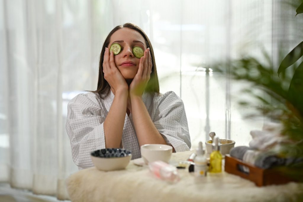 Une femme mettant une tranche de concombre sur ses yeux