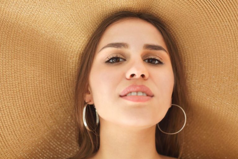 Une femme au visage bronzé portant un grand chapeau
