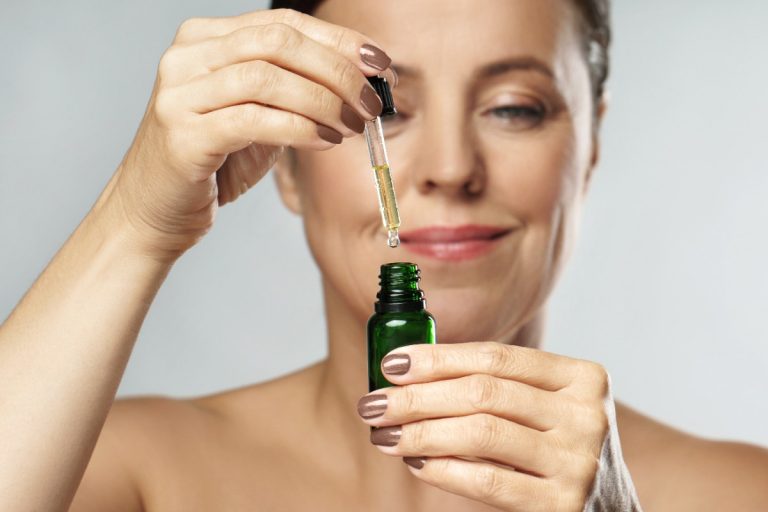 Une femme tenant une bouteille d'huile cosmétique pour le visage