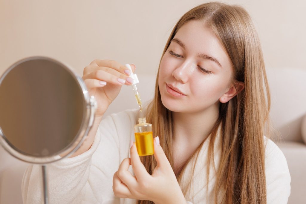Une jeune femme tenant un flacon d'huile pour le visage